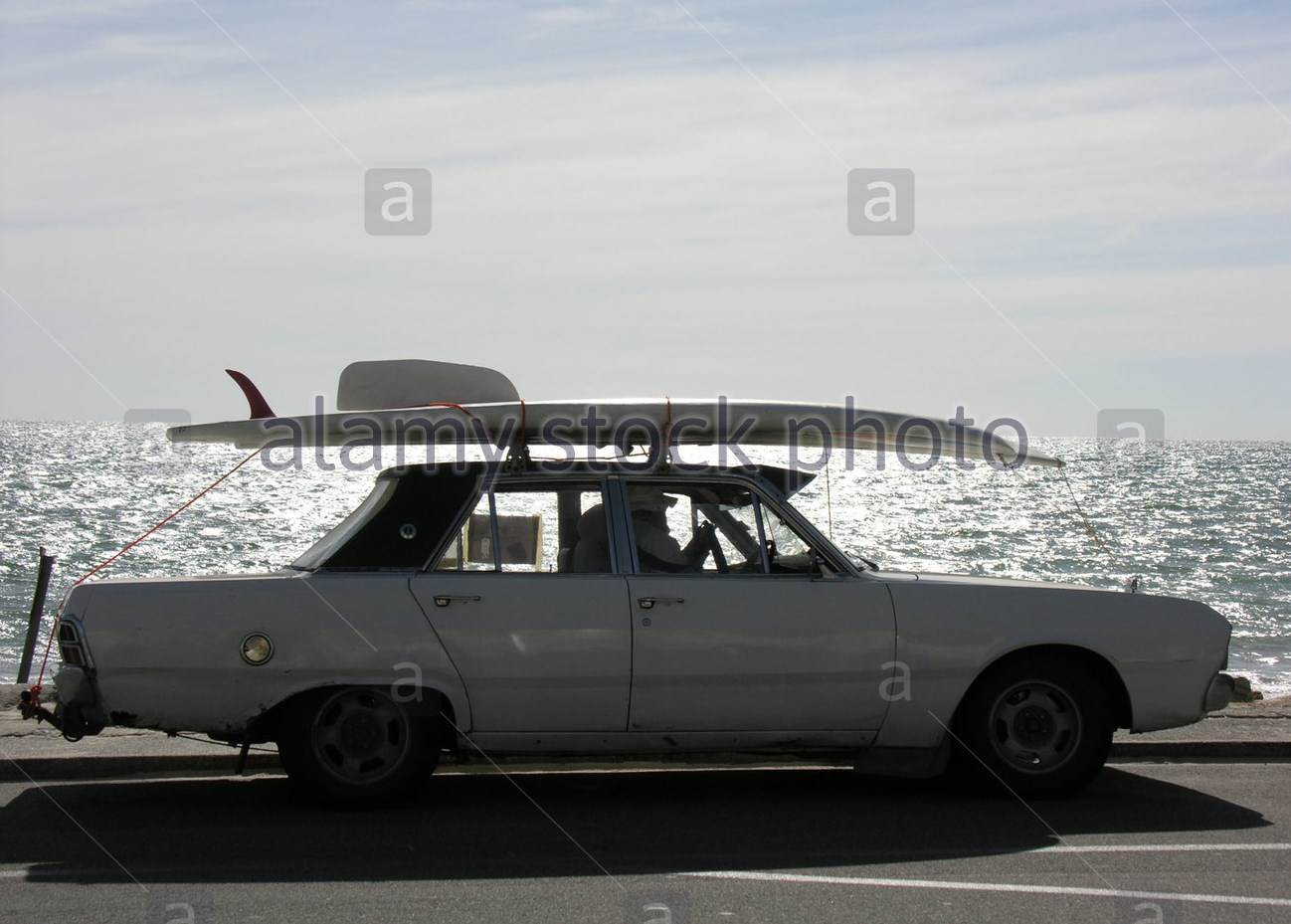 old-convertible-car-with-surfboard-on-roof-driving-on-esplanade-A5HM6E